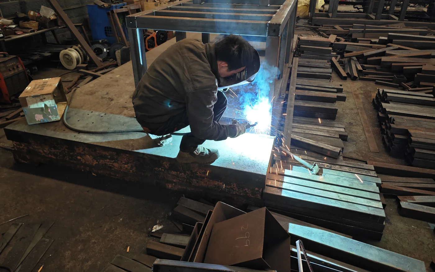 Worker welding industrial shredder frame