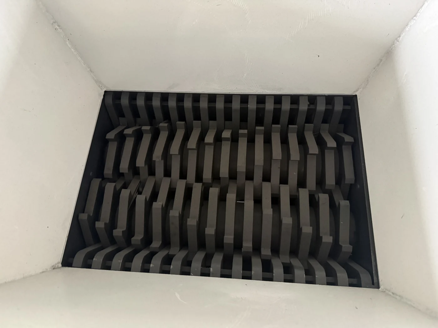 Intermeshing cutters inside a twin-shaft shredder feed hopper