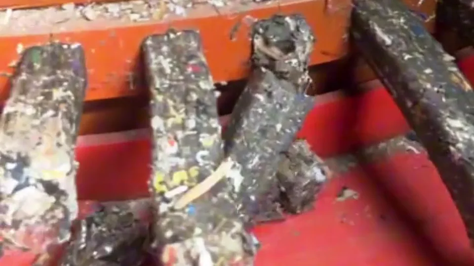 Compacted mixed-material blocks emerging from an orange downstream press